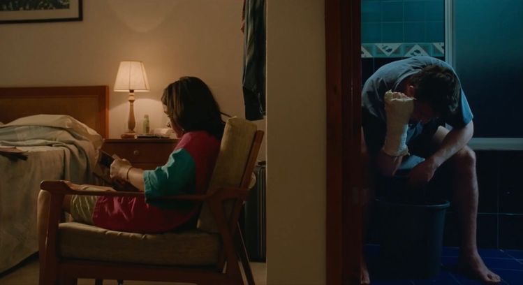 Girl sitting in a chair reading and man removing his cast.