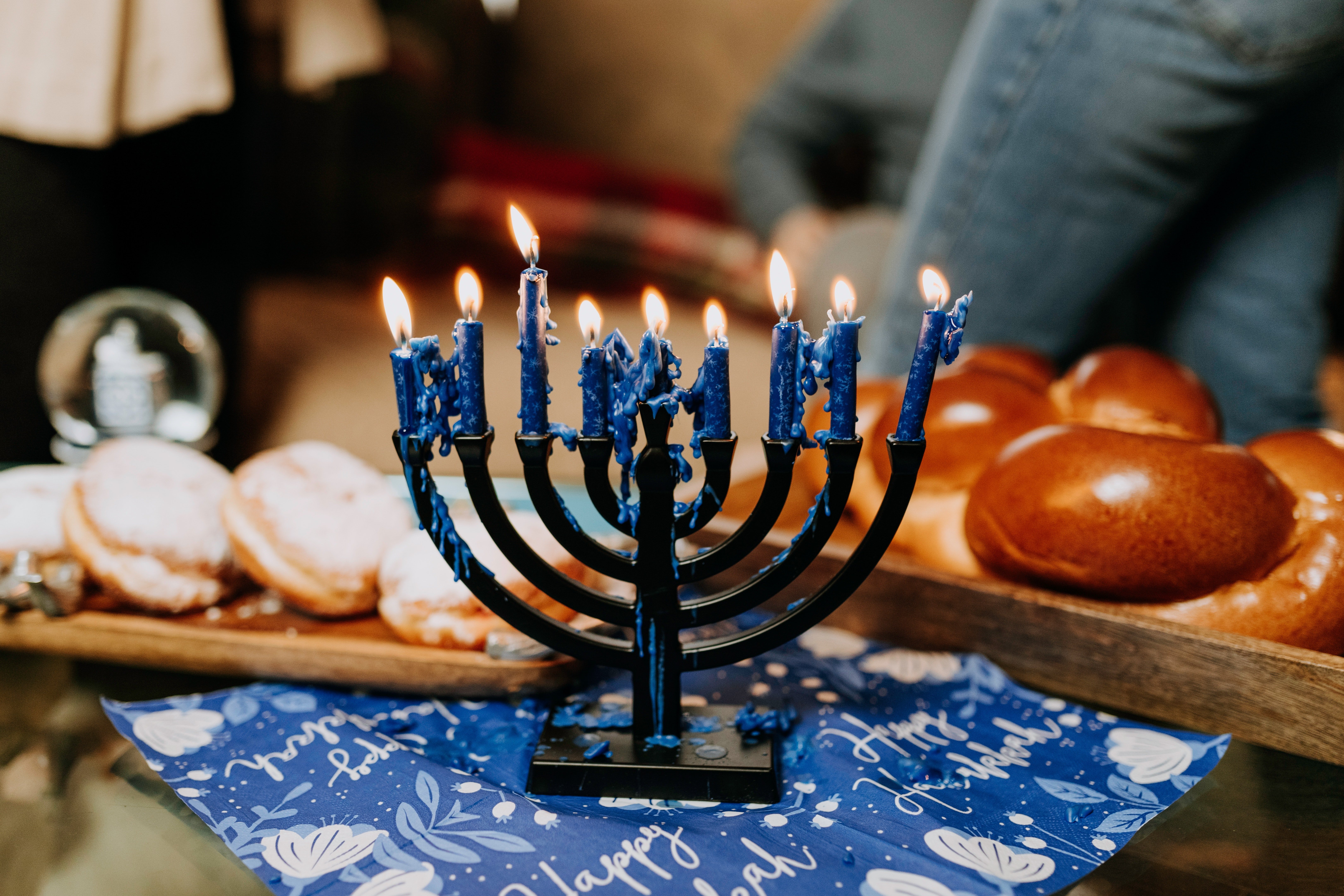 lit menorah surrounded by challah and jelly donuts for hanukkah