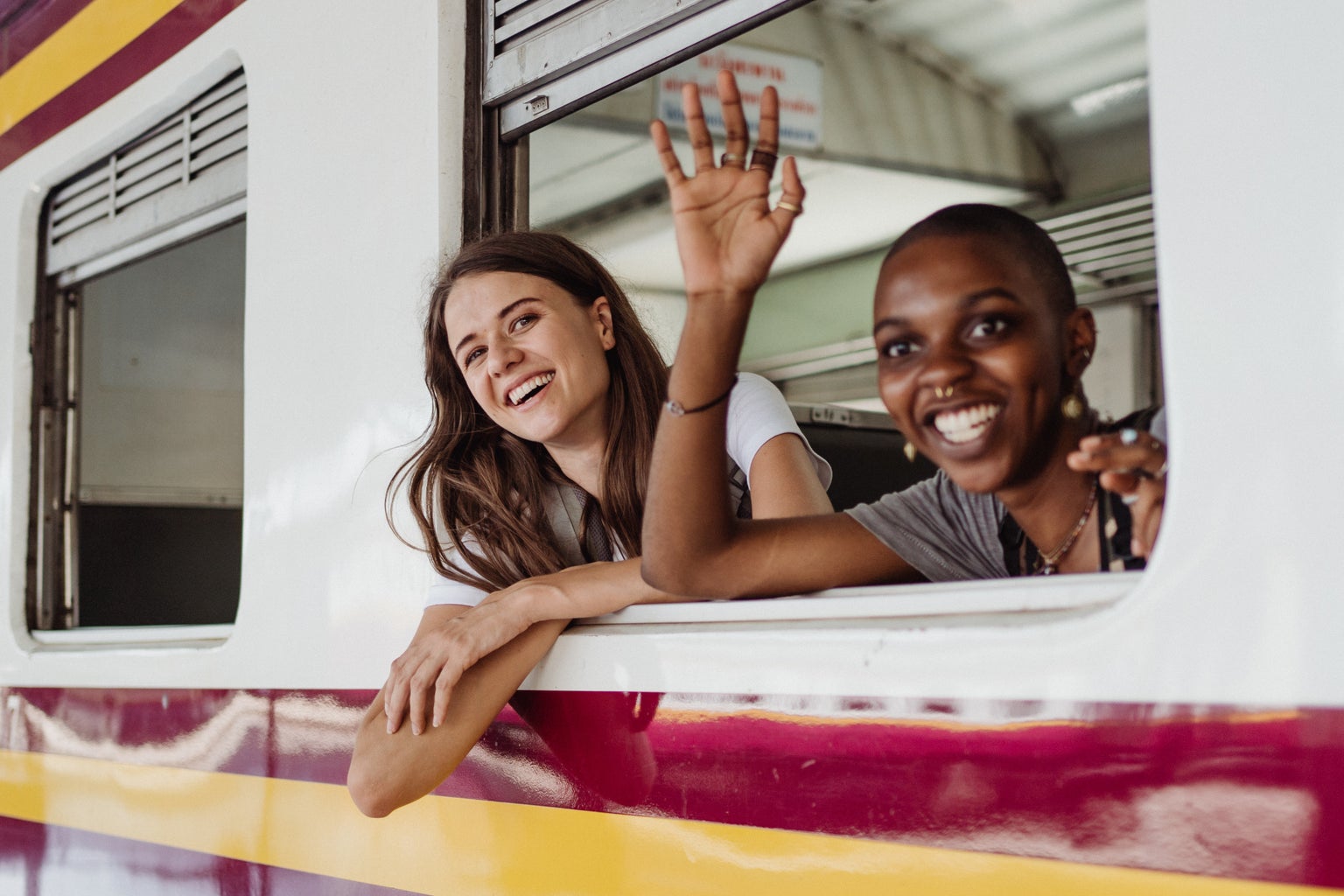 Two girls waving out a train window.