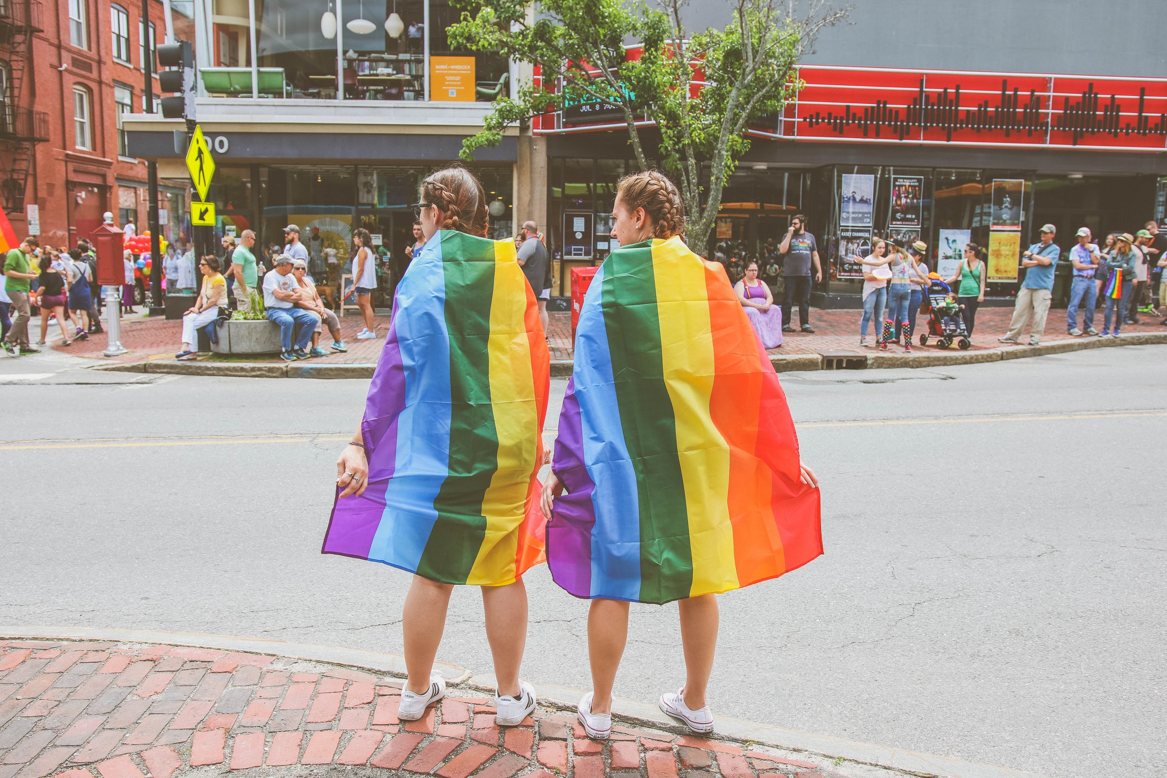 Two people wearing LGBTQ pride flags