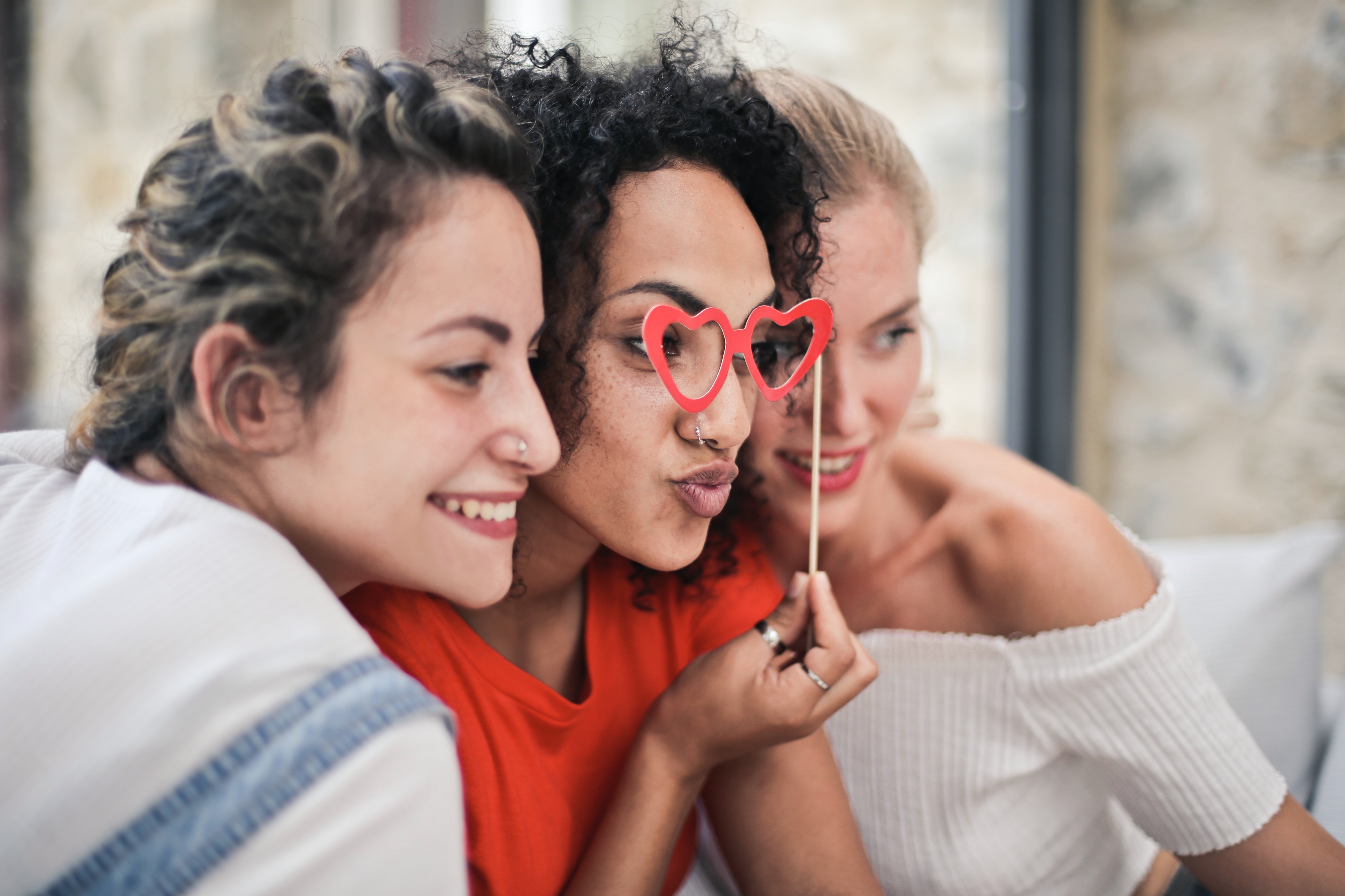 Three women side by side, center one wears heart glasses