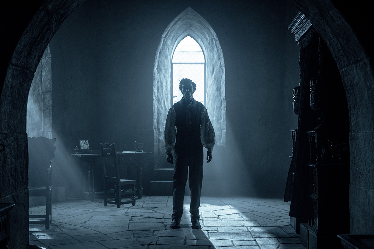 A man (Nicholas Hoult) standing in a dimly lit room. Still image from Nosferatu 2024.