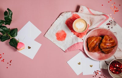 a pink table topped with a plate of food and cup of coffee