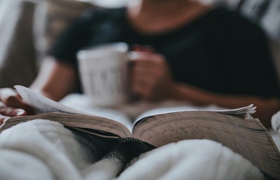 woman reading a book and holding a cup