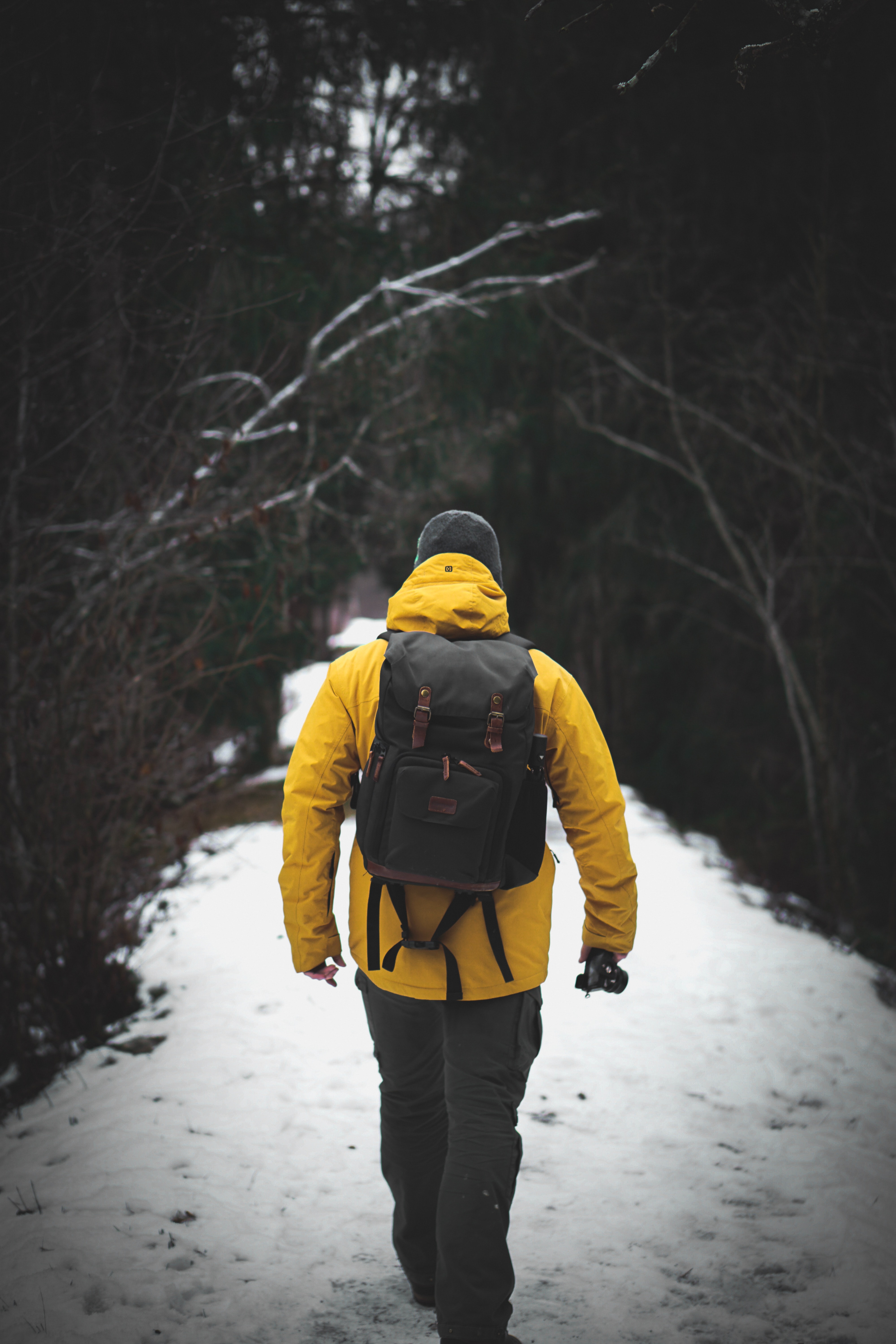man wearing yellow jacket walking on snow