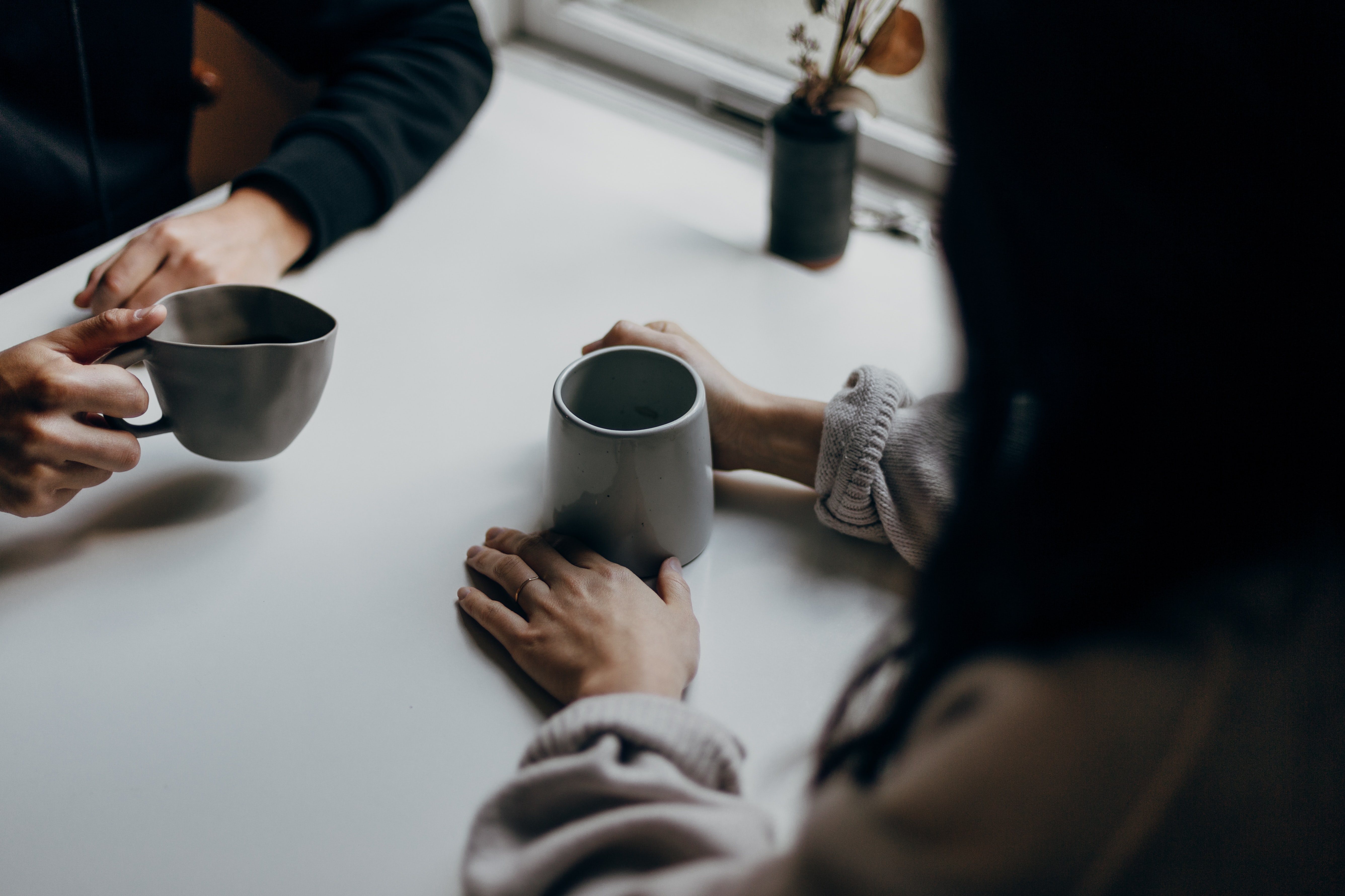 Two people having coffee over a white table