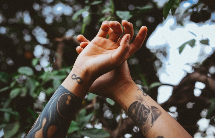 Hands raised in air with tattoo designs