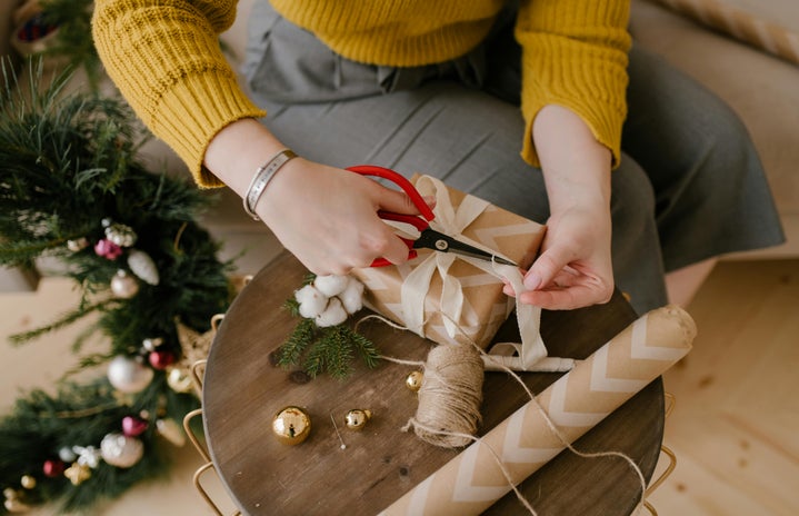 woman wrapping christmas gifts on brown table close up