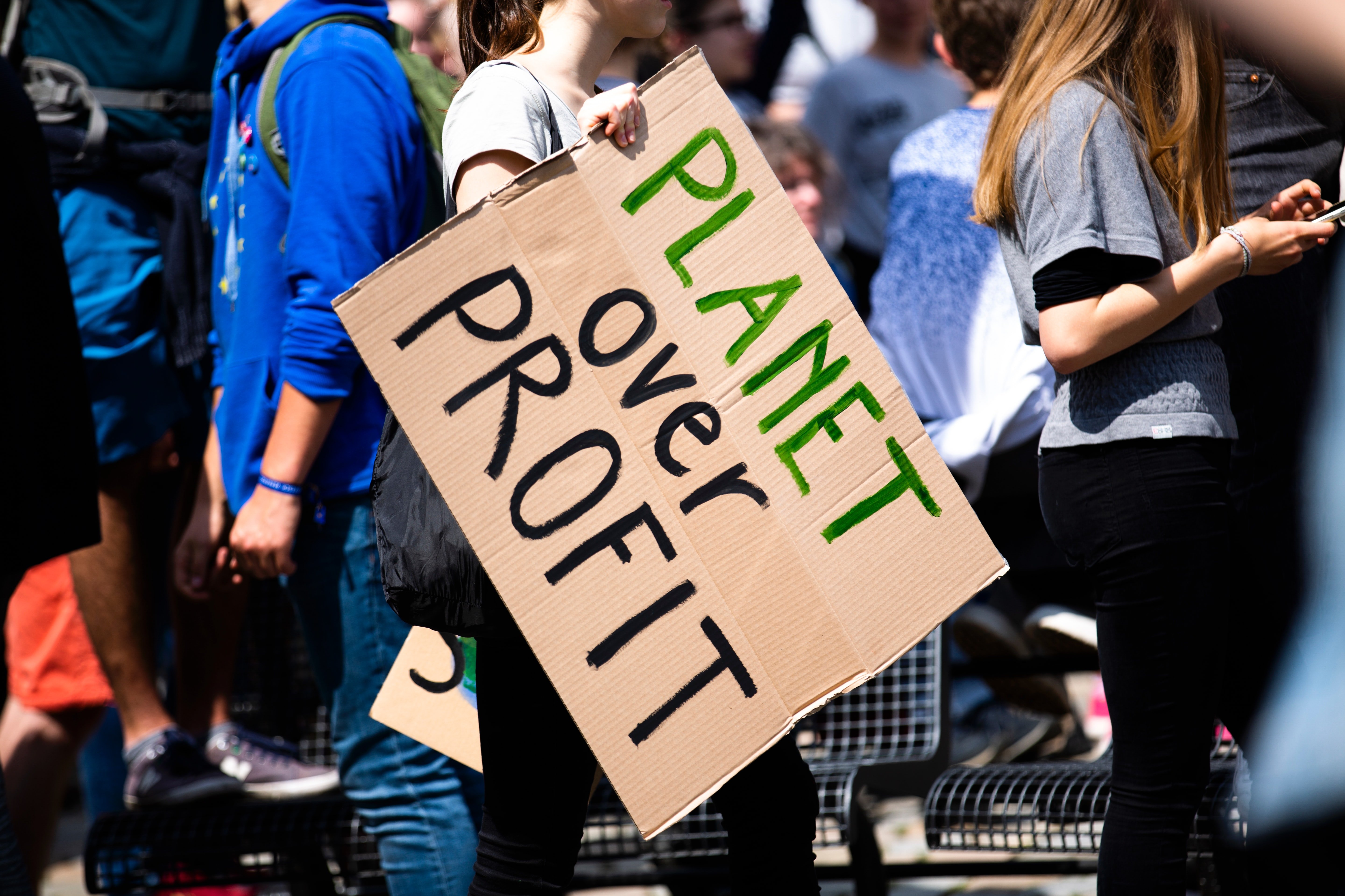 person holding a sign that says "planet over profit"