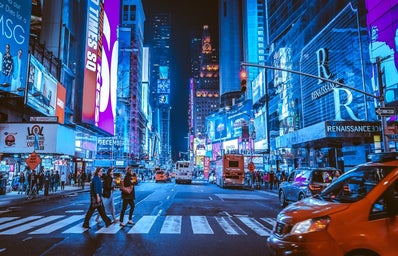 people walking on crosswalk in NYC at nighttime