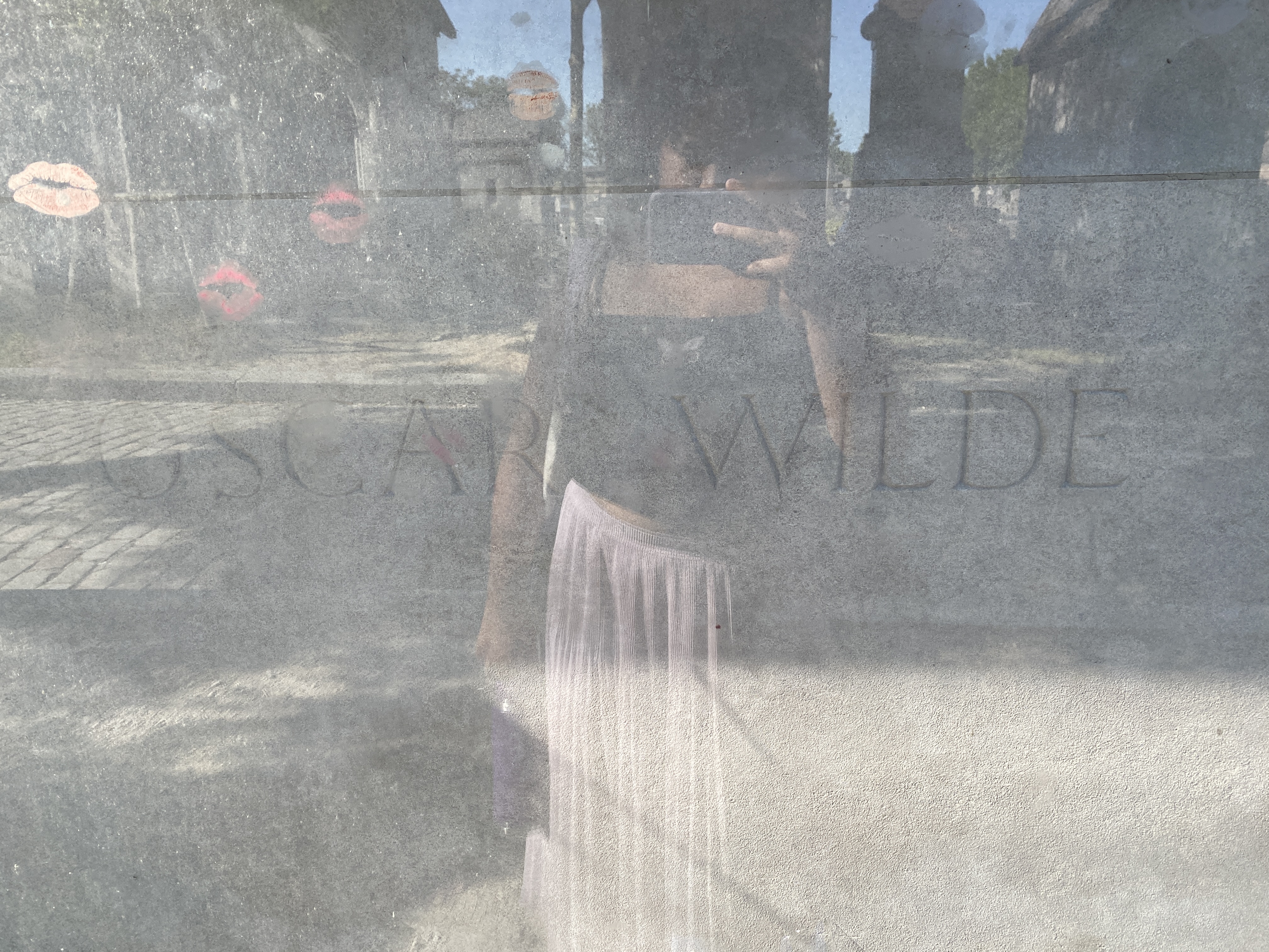 A picture of Oscar Wilde\'s grave with a woman reflected through taking the photo
