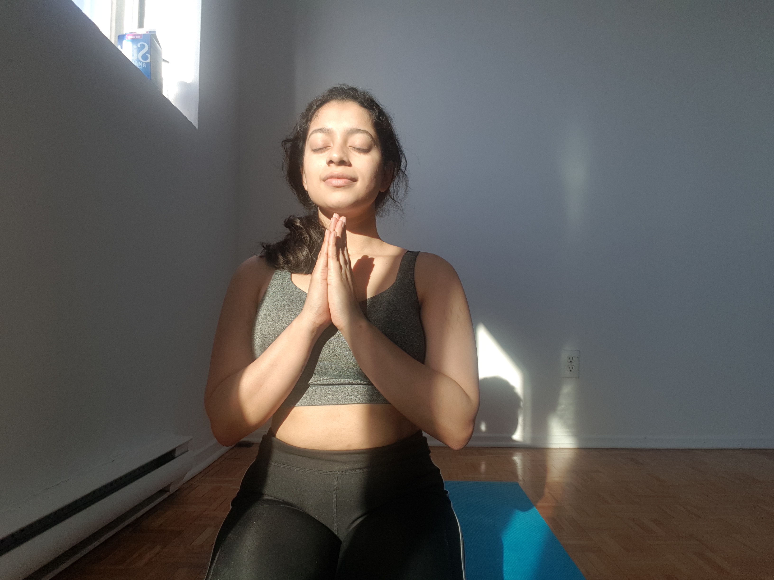 Woman with hands joined and eyes closed in namaste.