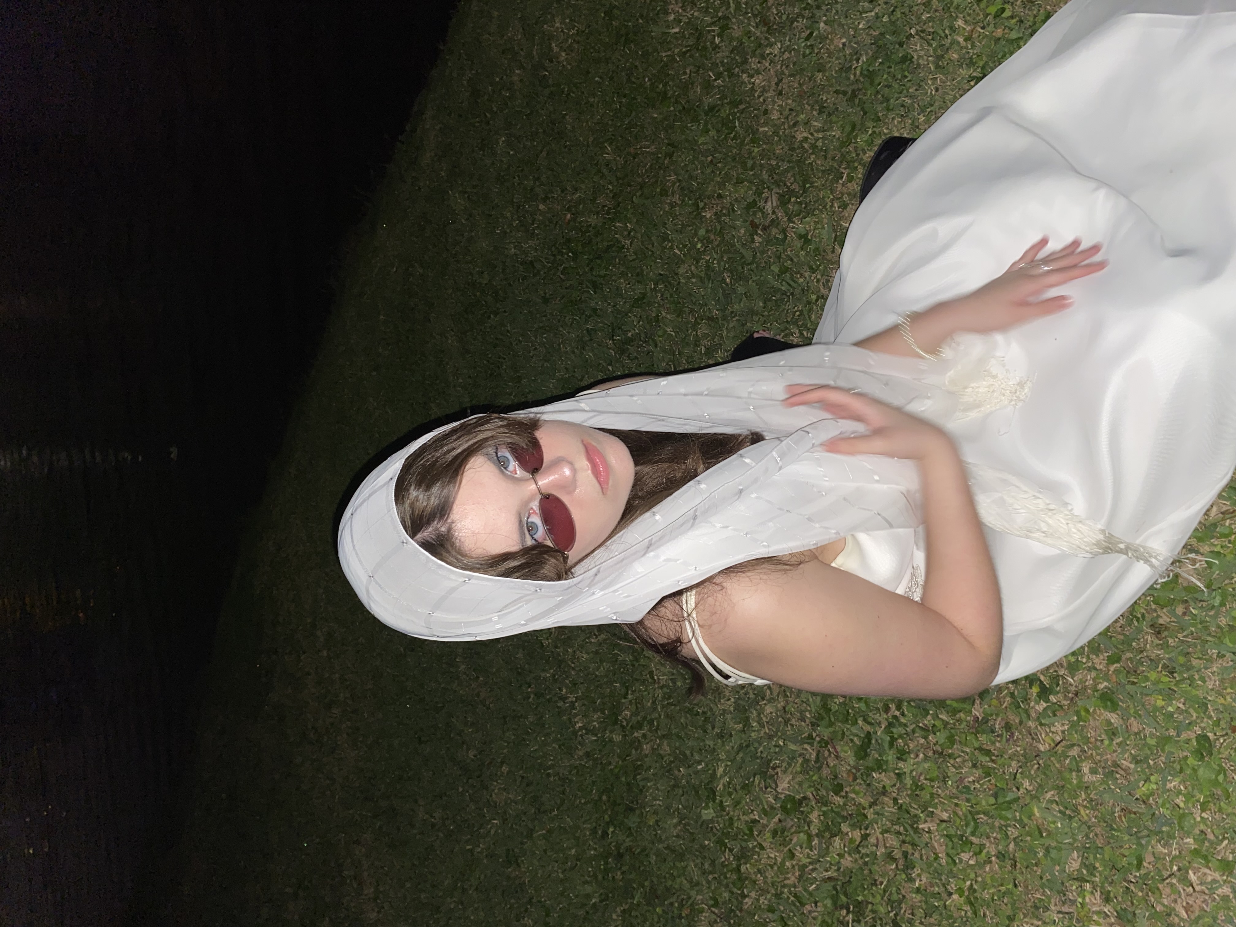 Girl in grass at night wearing white dress and headdress
