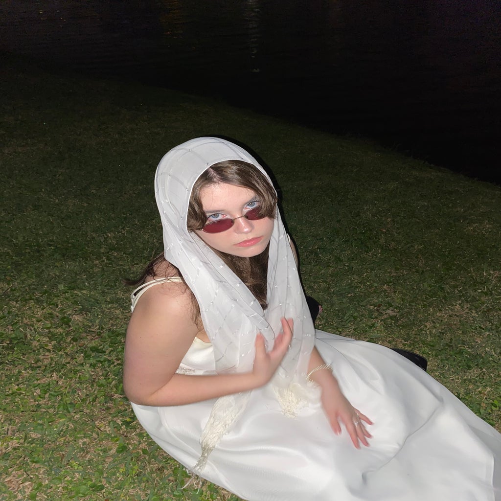 Girl in grass at night wearing white dress and headdress