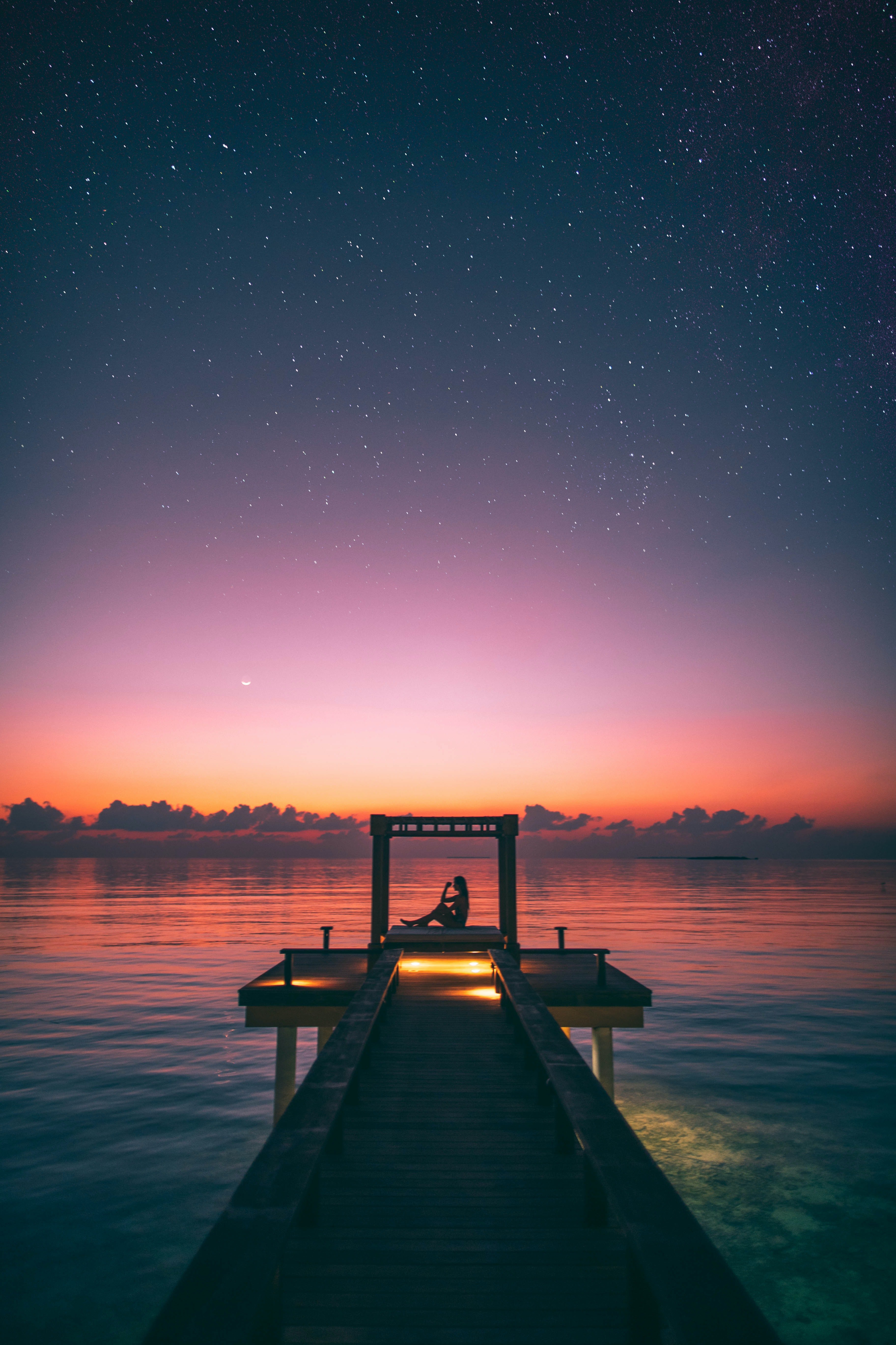 Person Sitting on Boardwalk at sunset