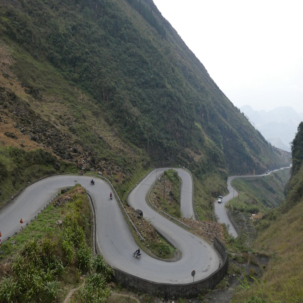 Motorbikes drive on a winding road in the hills of Vietnam