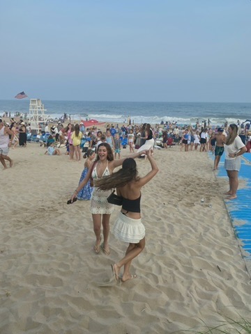 Two girls dancing on a crowded beach