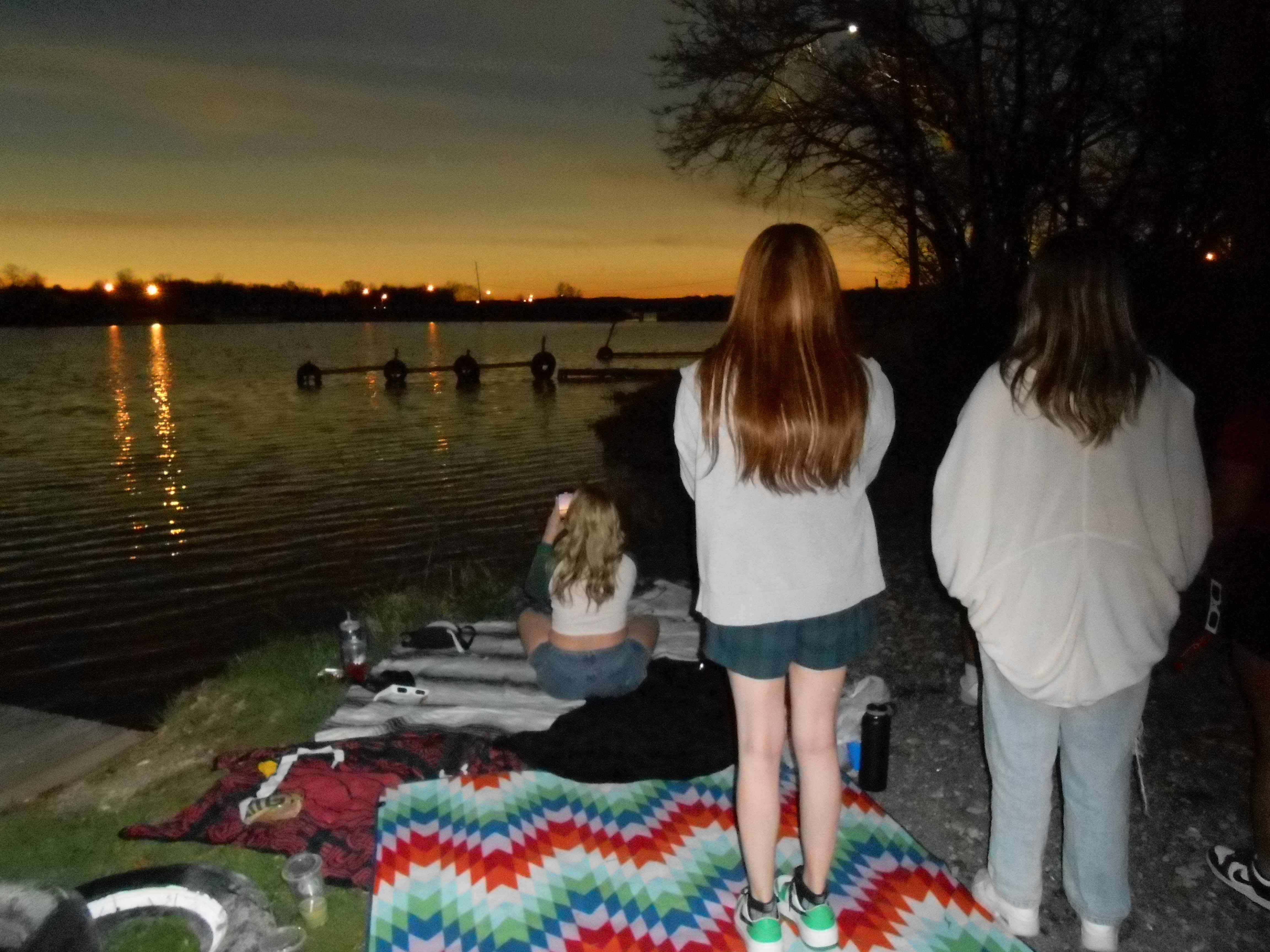 Solar eclipse over water with people watching