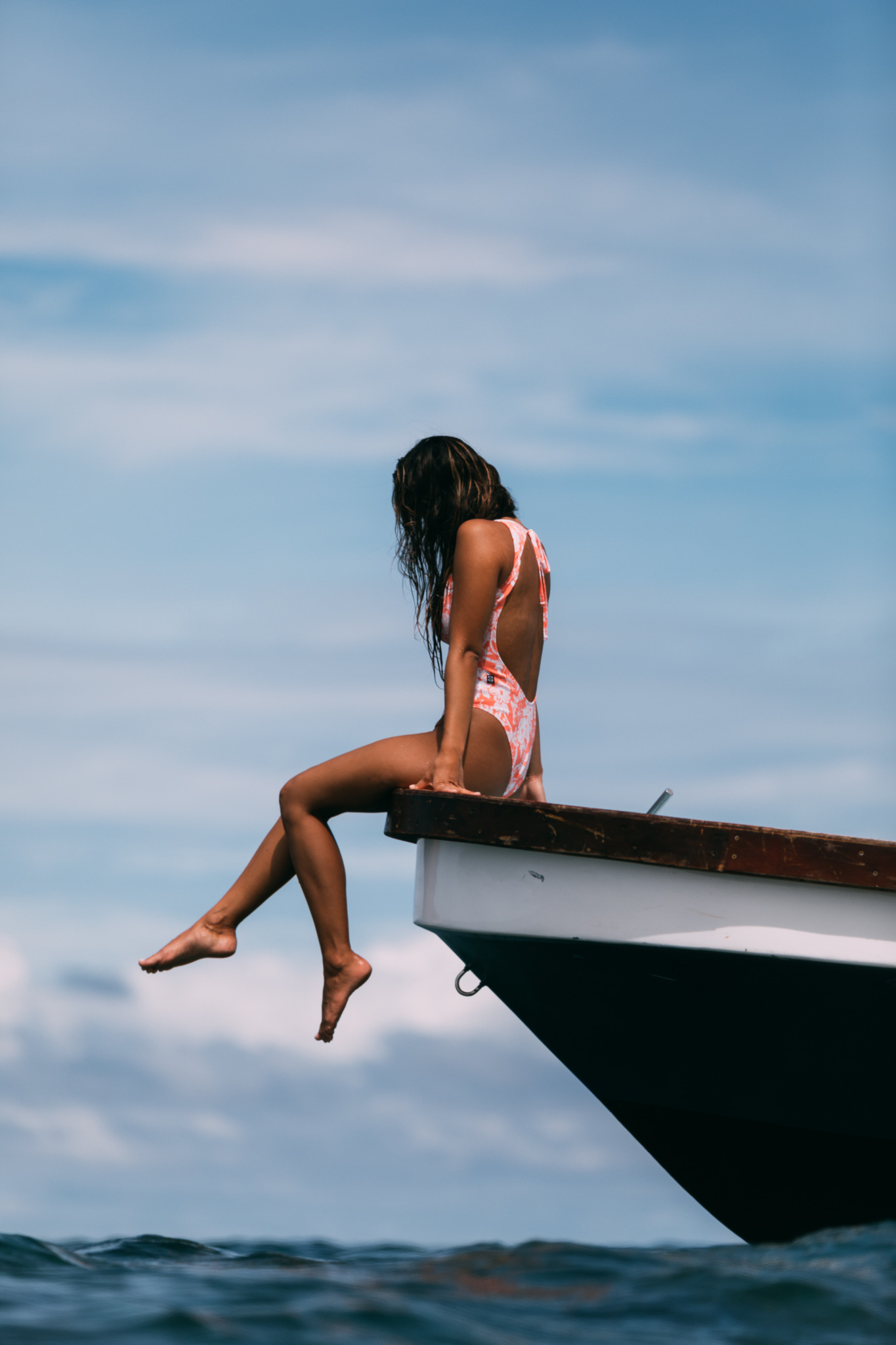Influencer Eryn Krouse sitting on the edge of a boat of the ocean.