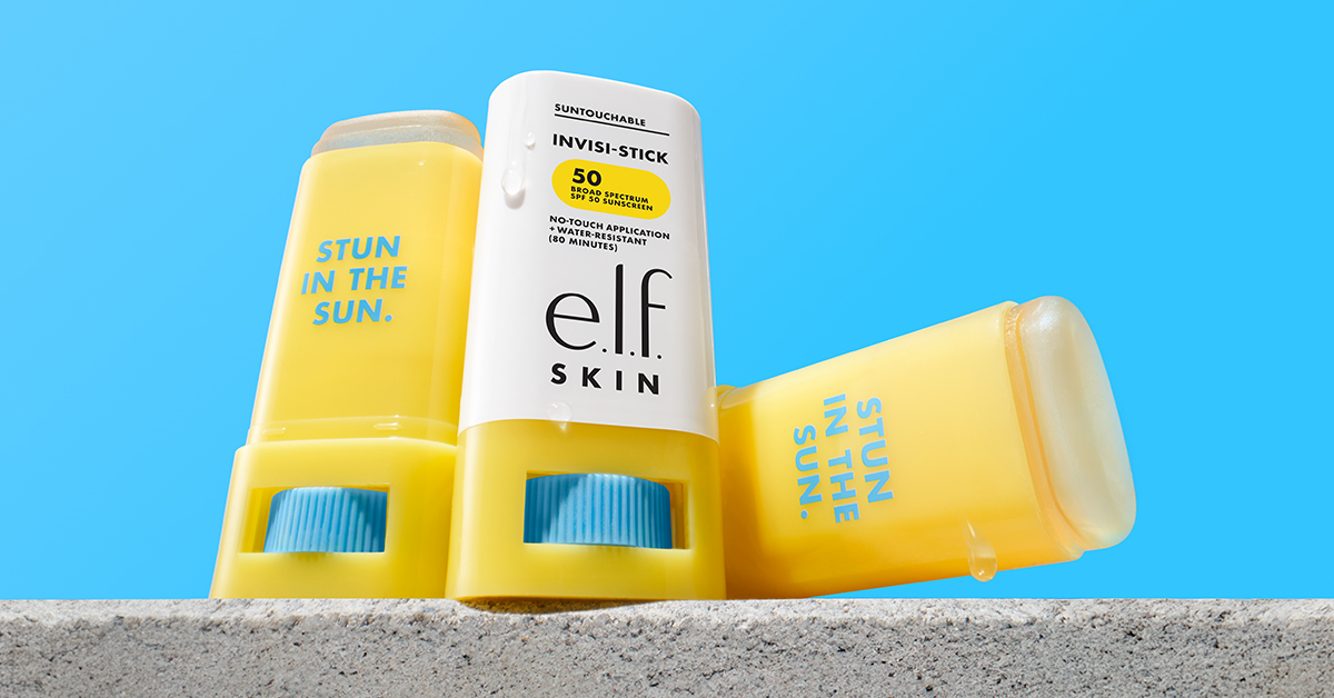 three e.l.f. Cosmetics sunscreen sticks arranged on a ledge with a blue background