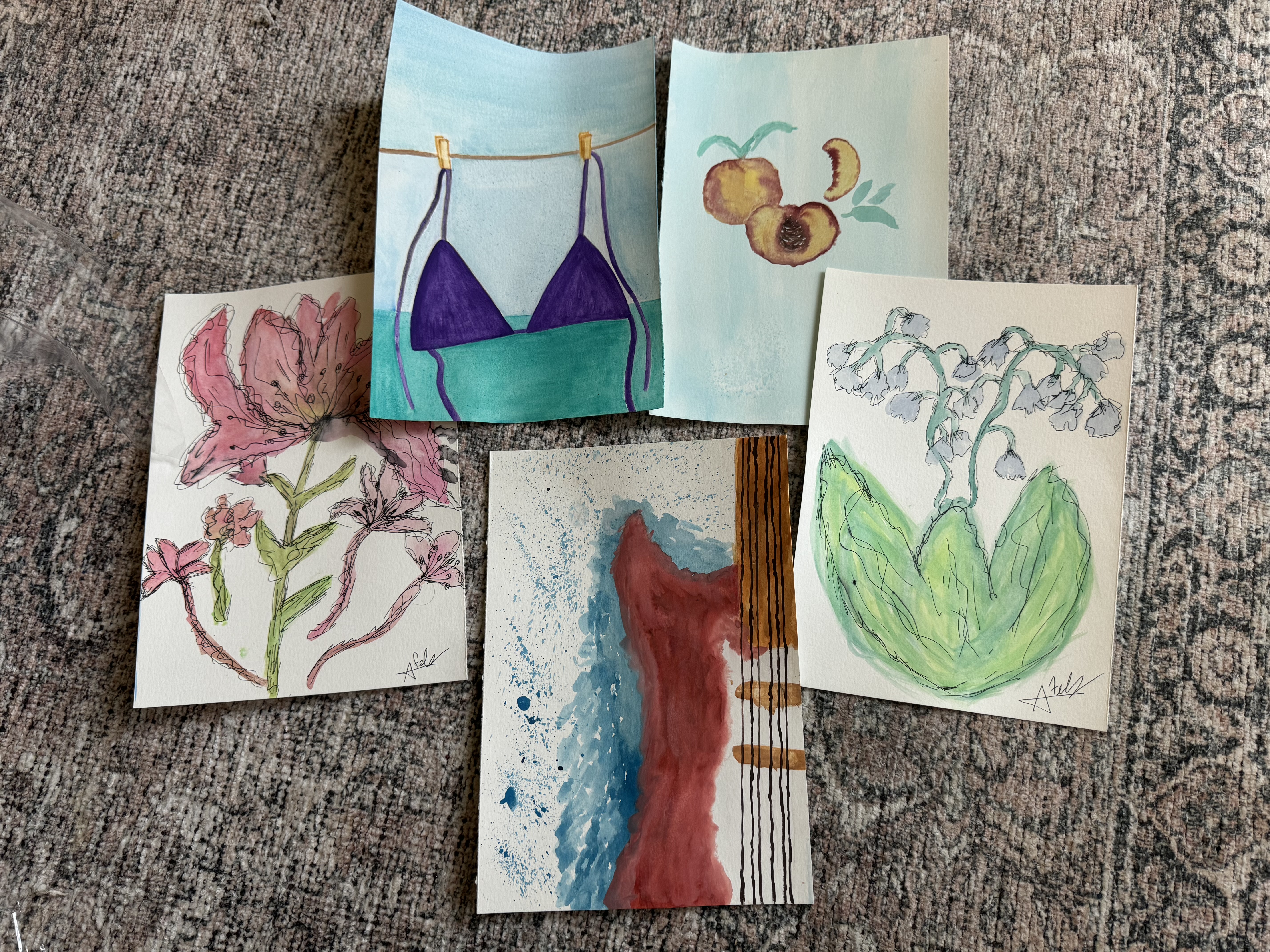 Five watercolor paintings laid out on ground