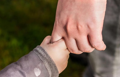 A child\'s hand gripping an adults finger