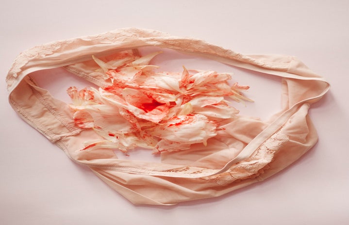 Beige colored underwear with beige/white colored flower petals on top stained with a red dye