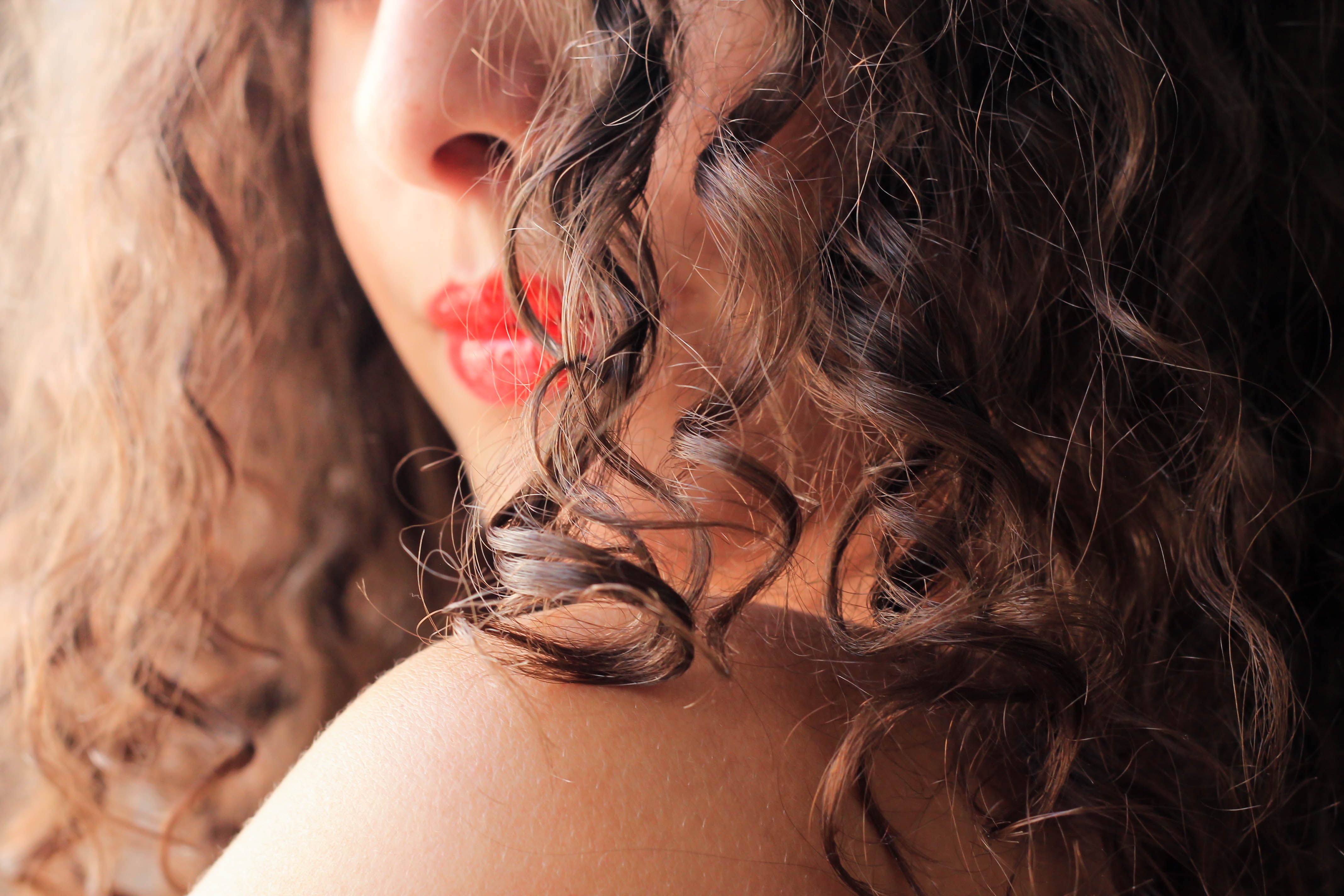 A woman looks over her shoulder with the camera focusing on her curly hair.