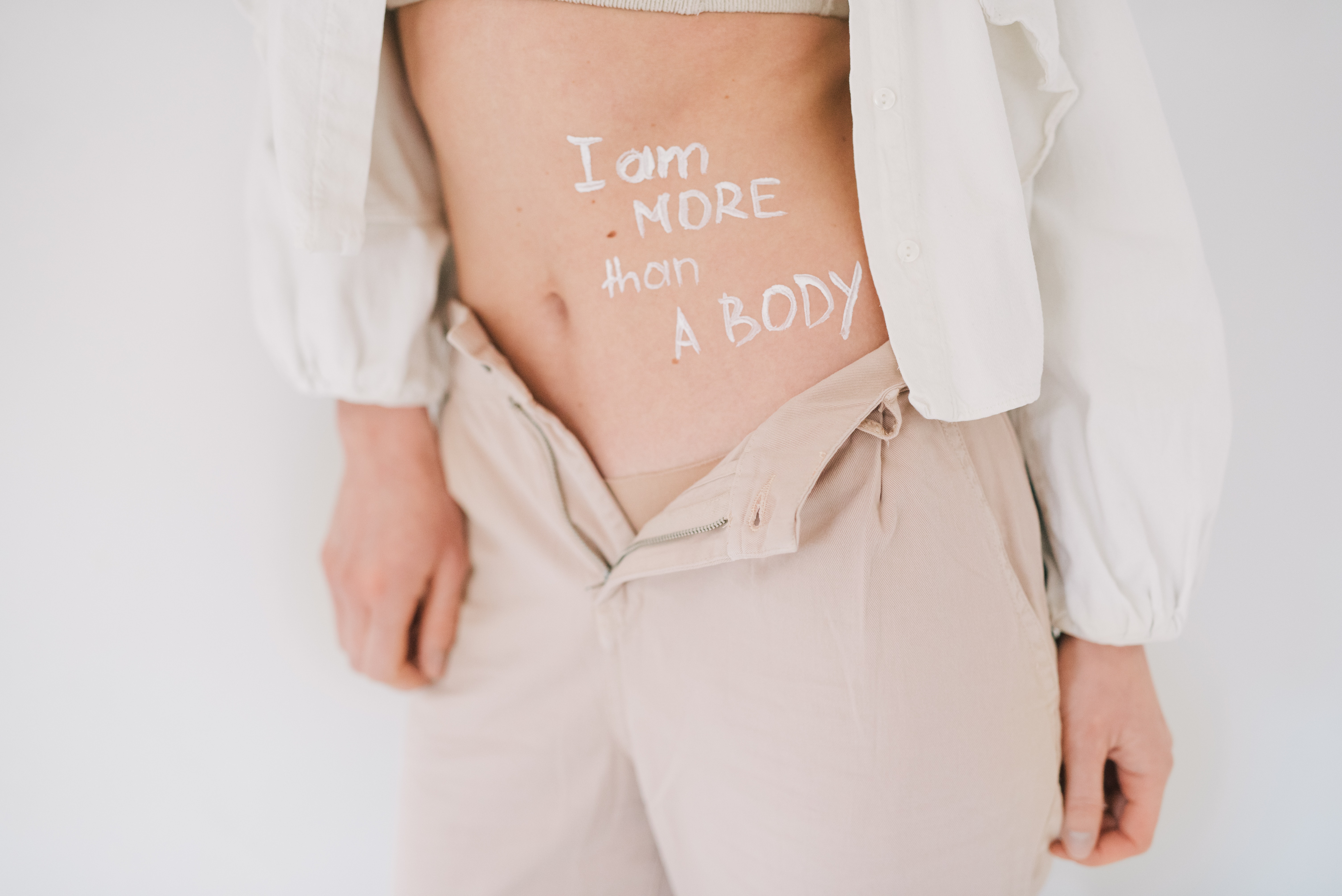 A model\'s exposed stomach reads \"I am more than a body.\"