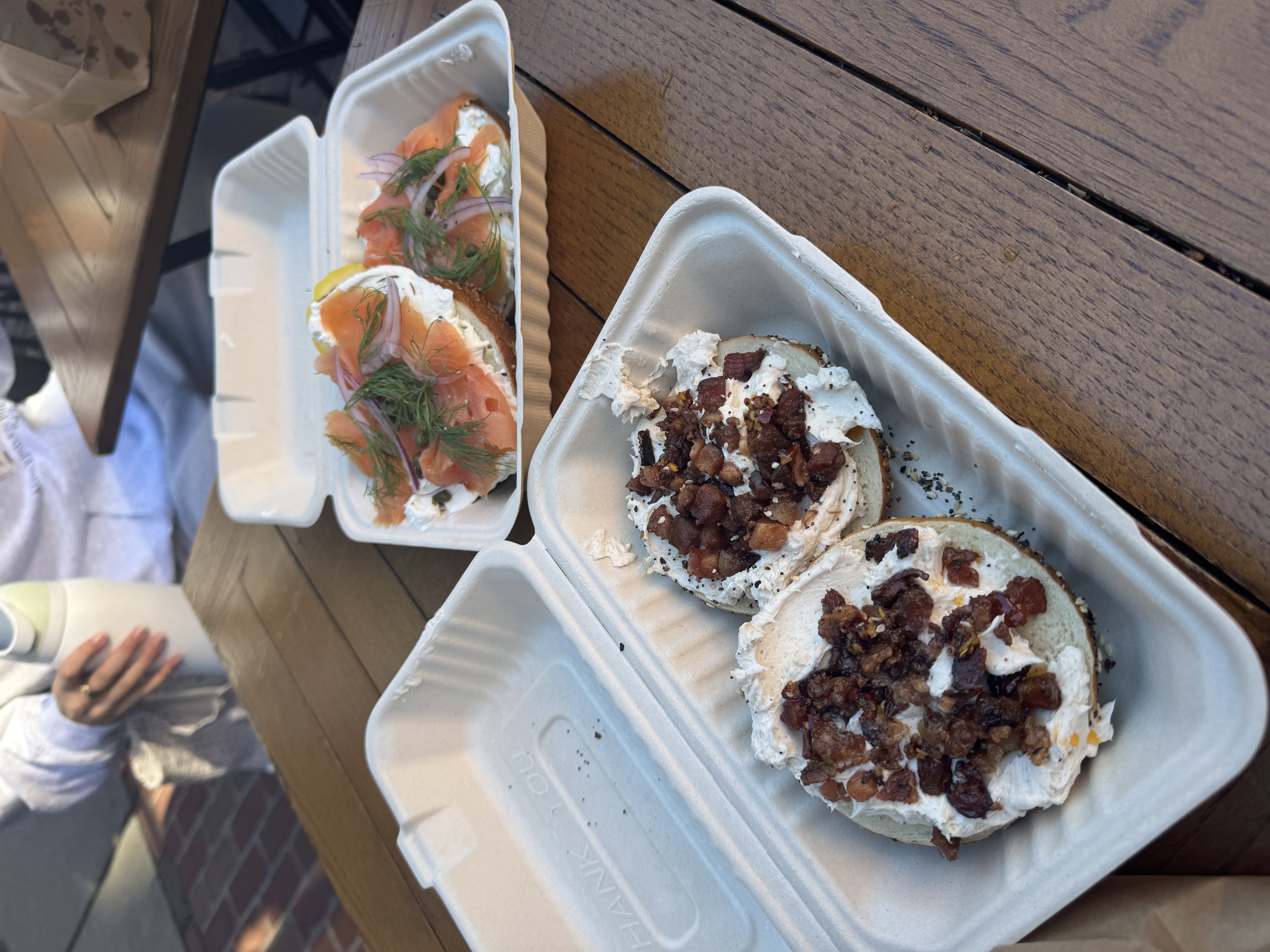 two open containers with bagels inside on a table