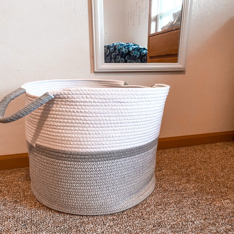 gray and white basket on floor right in front of mirror