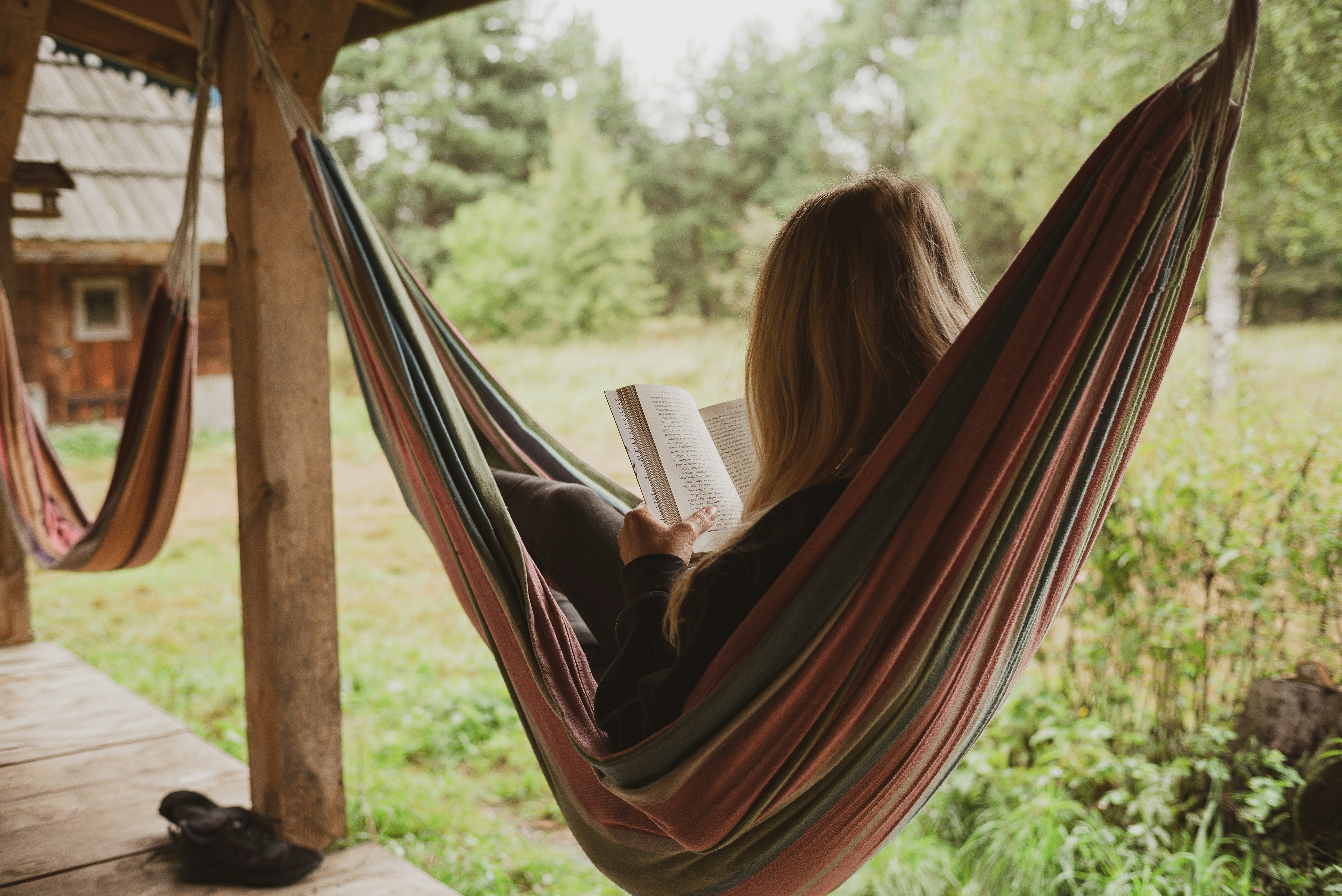 Woman laying in a hammock with a book.