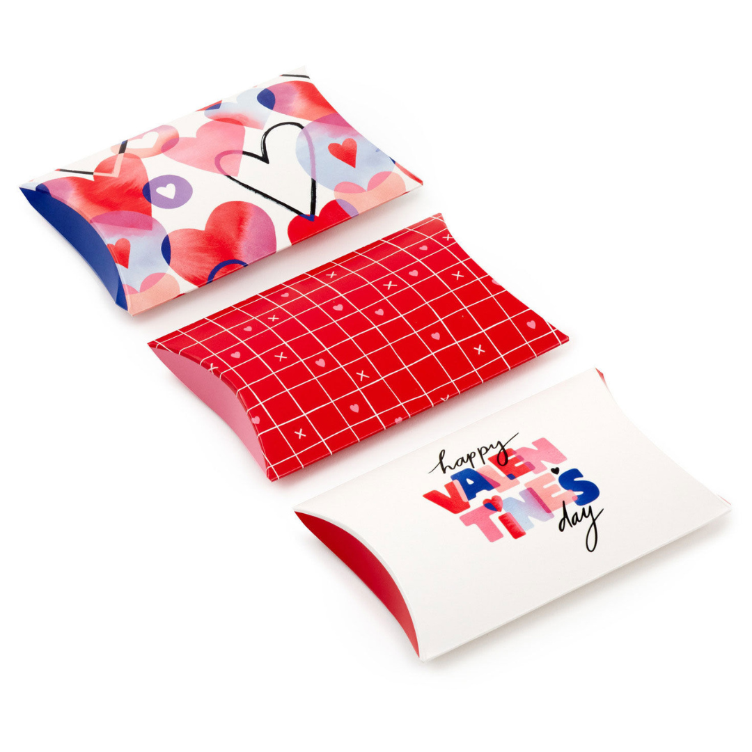 three paper gift boxes with different red, white, blue, and purple designs on them
