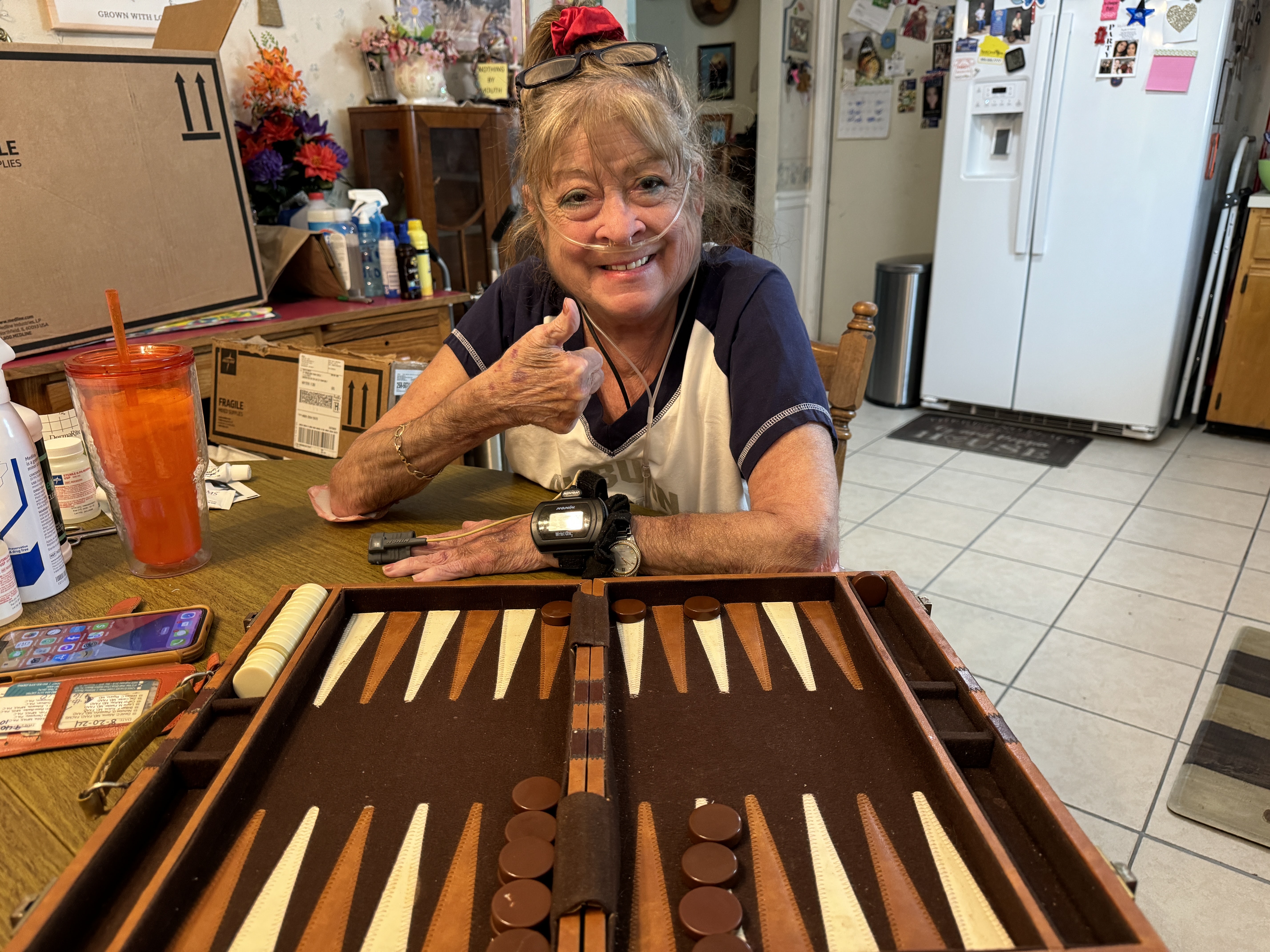 Grandmother smiling with a thumbs up over backgammon