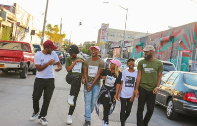 A group of black friends walking through a street happy and hanging out