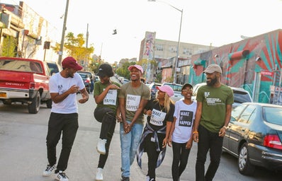A group of black friends walking through a street happy and hanging out