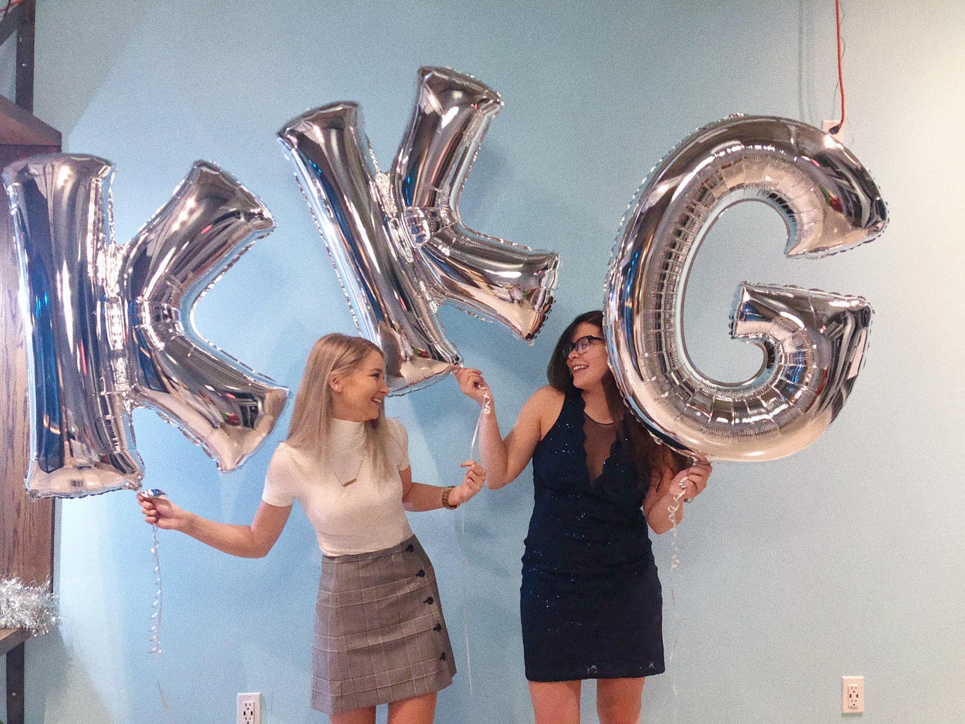 two sorority sisters holding silver KKG balloons