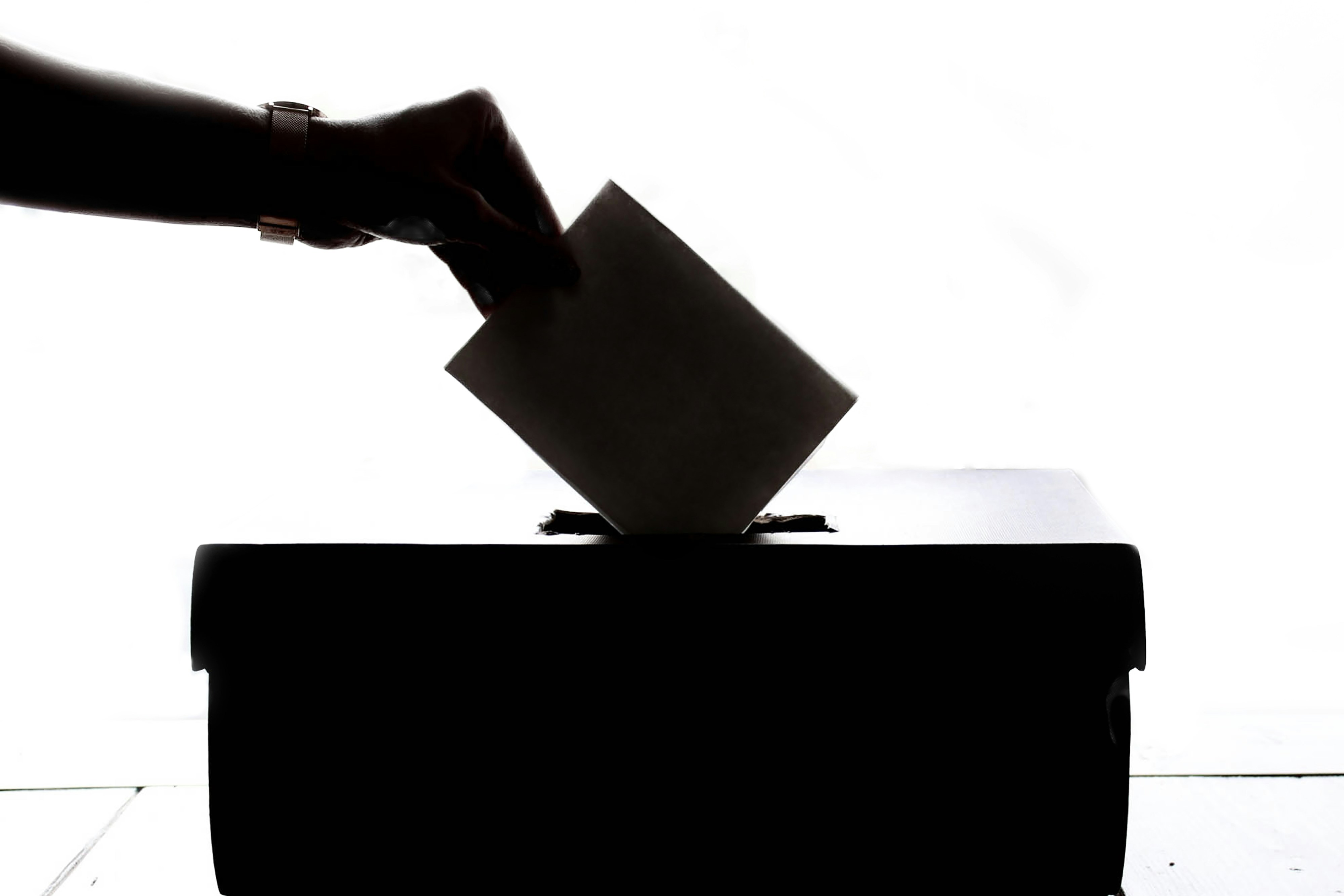 a person is casting a vote into a box.
