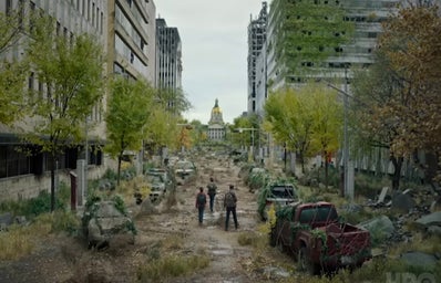 A imagem mostra uma cidade abandonada com três pessoas andando pela rua.