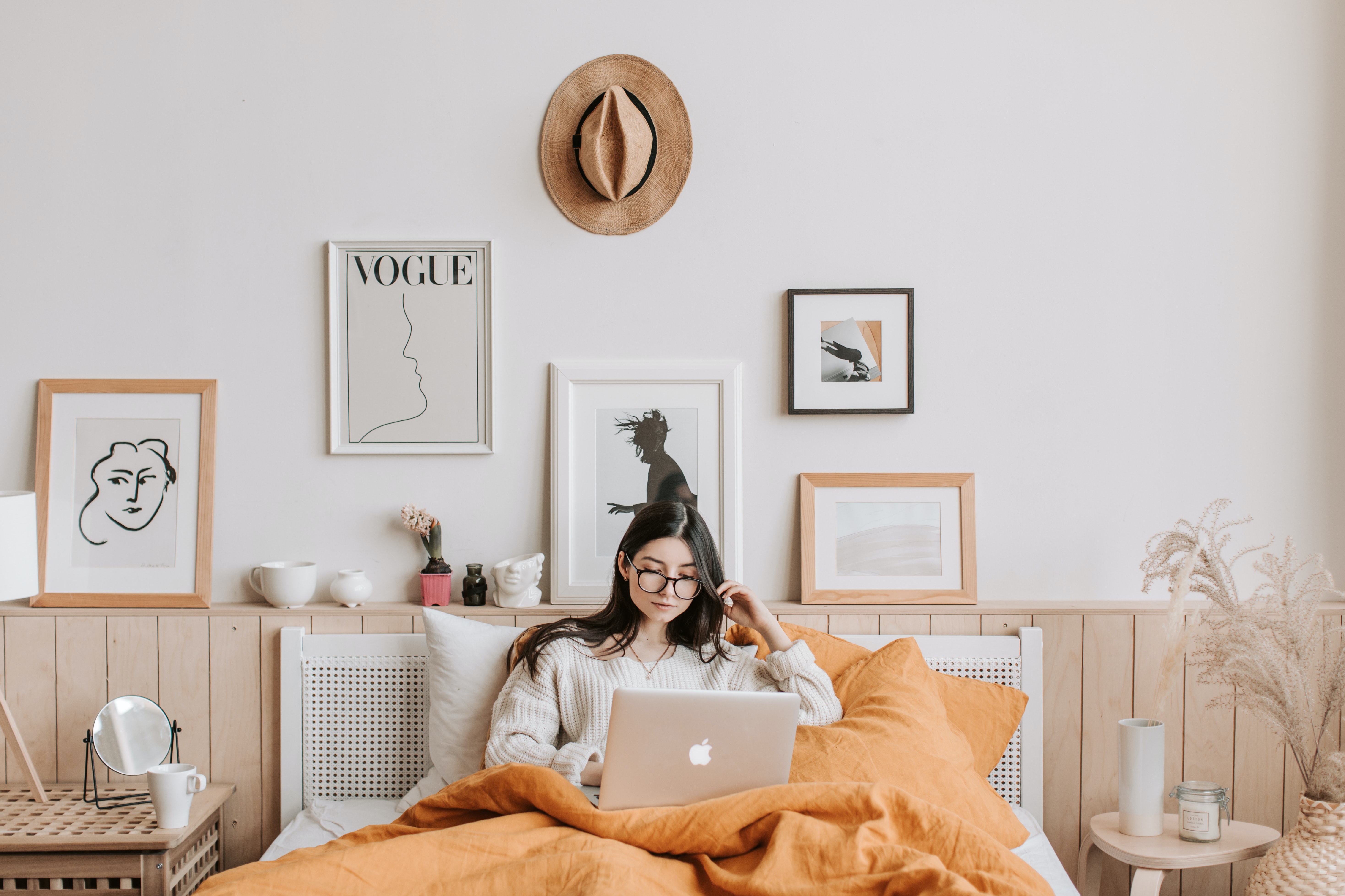 A woman sits on her bed using a laptop.