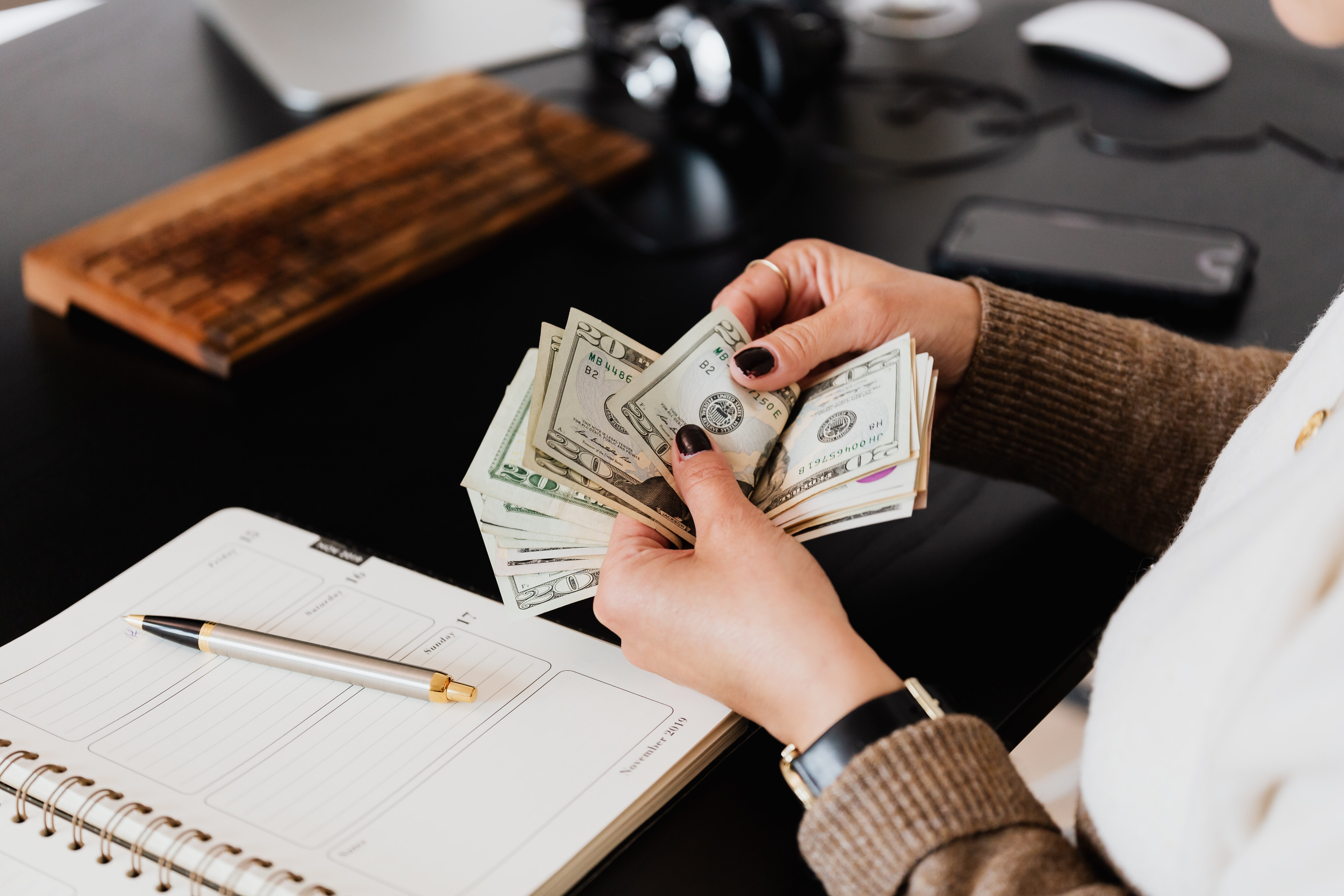 A woman counts money at her desk.
