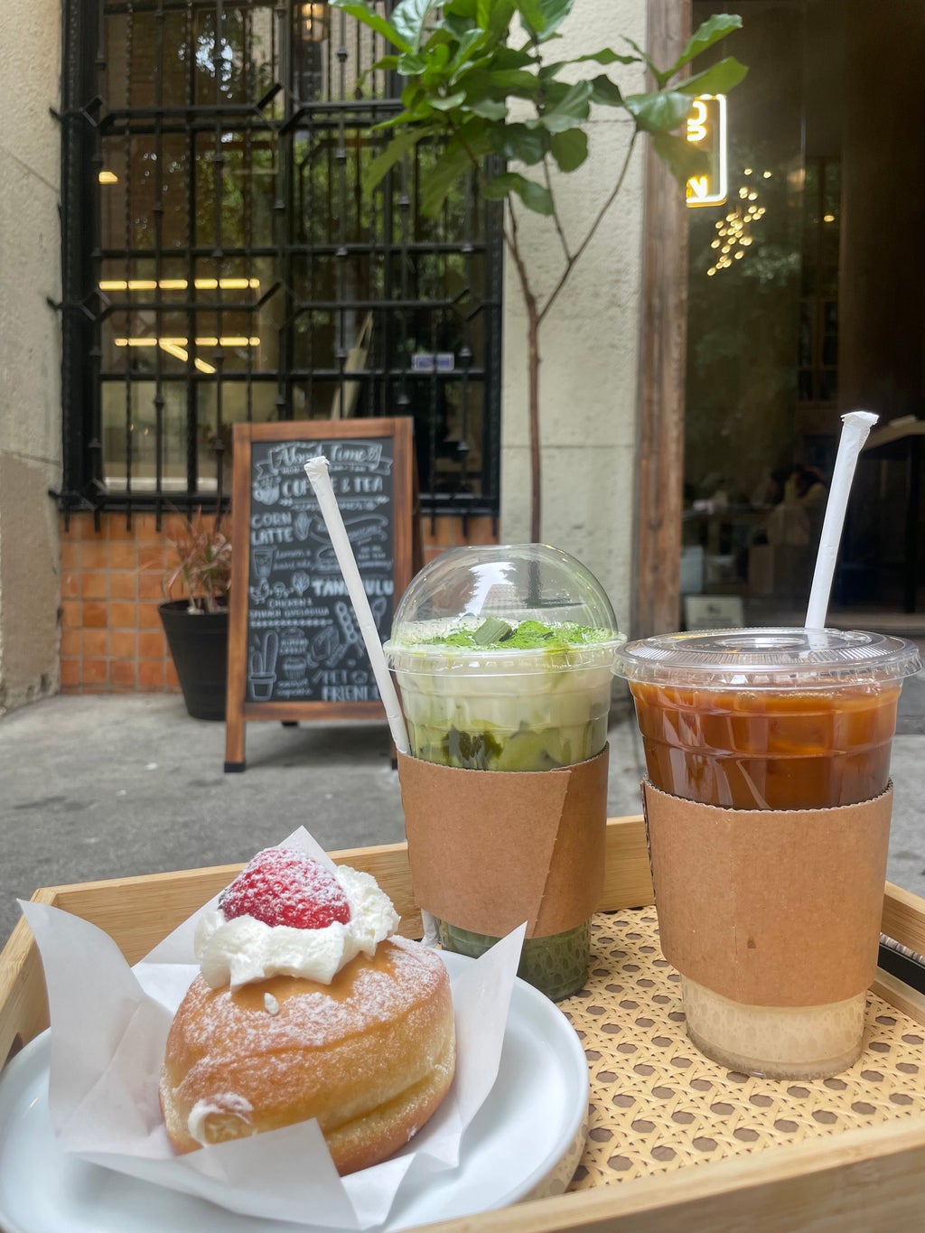 cup of iced coffee and matcha with a strawberry donut