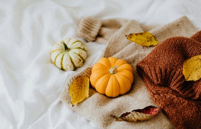 Orange pumpkin next to brown knitted sweaters