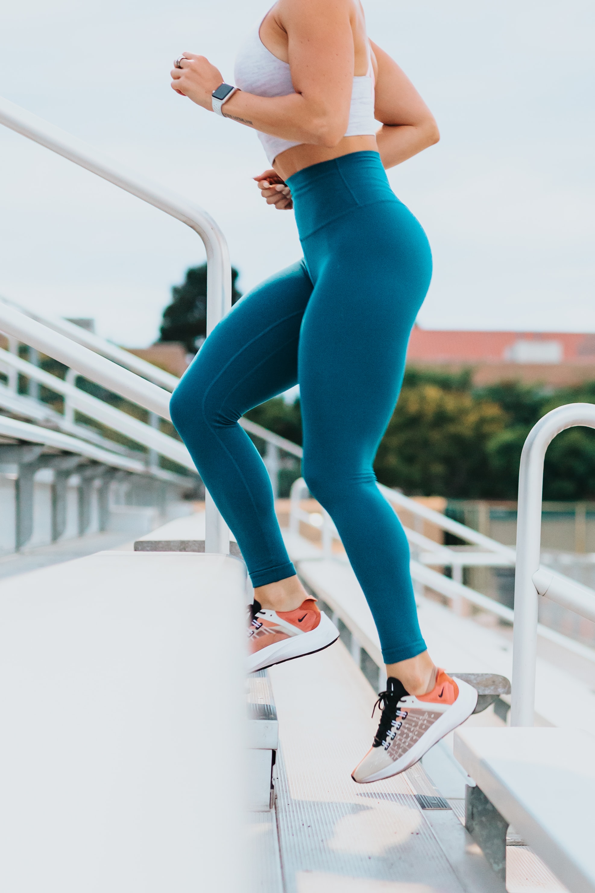 Woman in leggings running up stairs outside