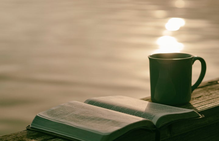 open book with mug in front of water