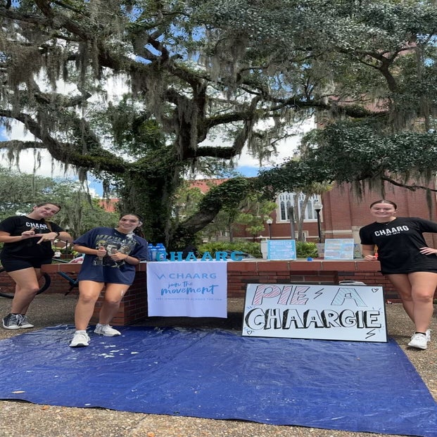 Three girls outside in front of club/organization table