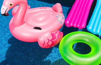Pink inflatable flamingo in pool next to neon green inflatable.