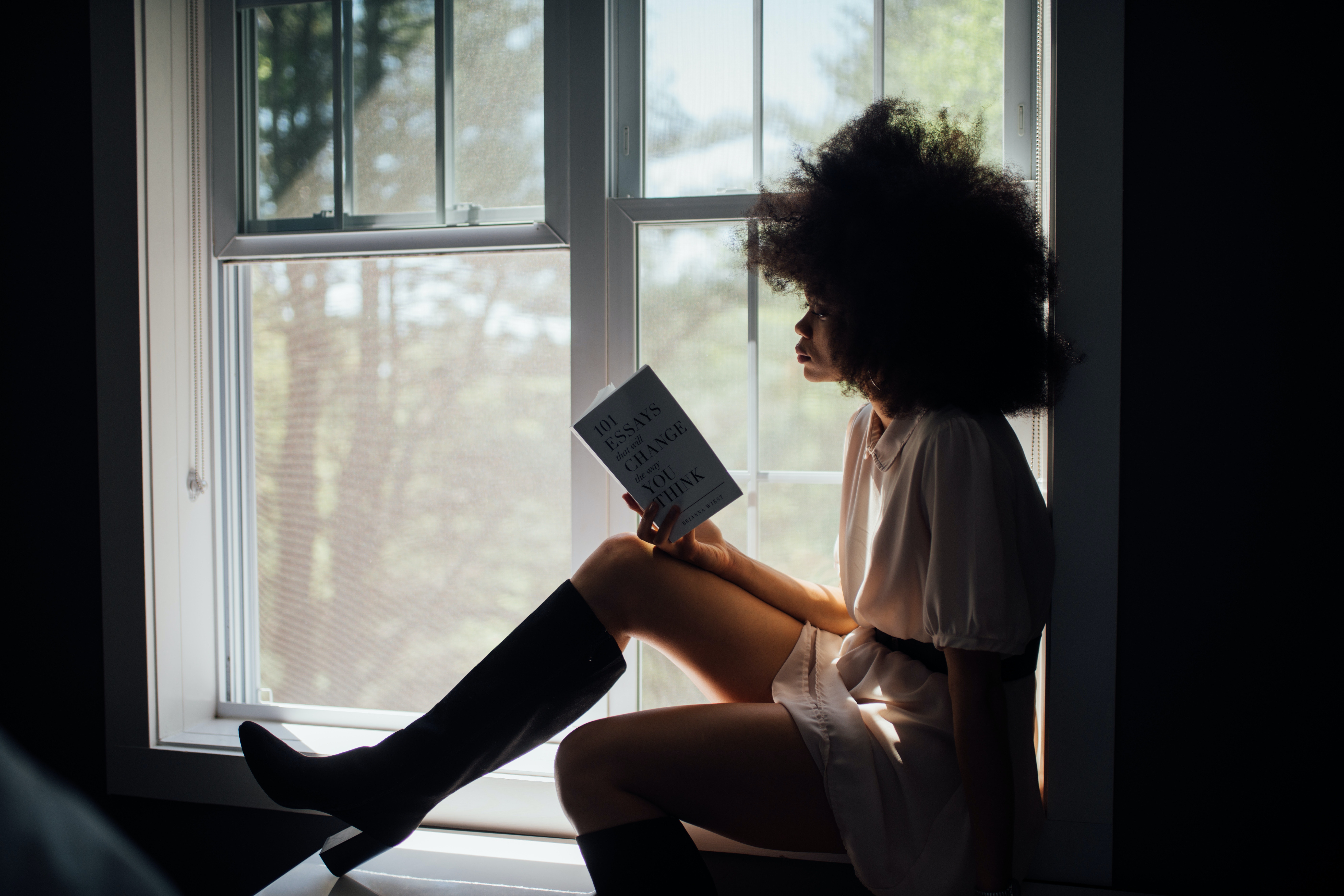 Woman reading a book in a windowsill.