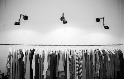 Rack of clothes hanged up with lights above.