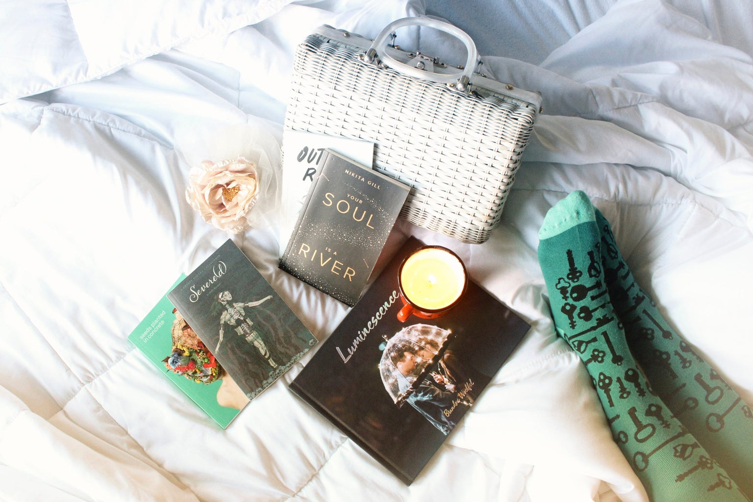books, a candle, a purse, and a flower